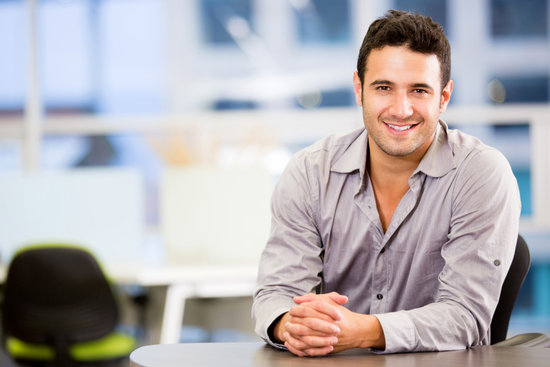man sitting at a desk smiling waiting for an interview in the insurance industry