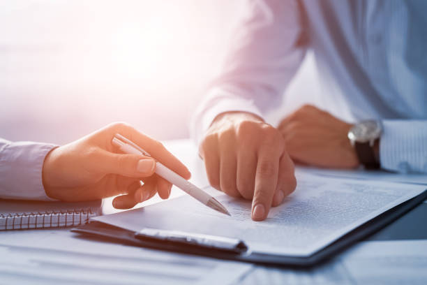 A finger pointing and a pen pointing at the same document on a clipboard. 